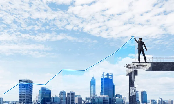 Businessman in suit drawing graphs on modern statistical media interface while standing on broken bridge with cityscape on background. 3D rendering.