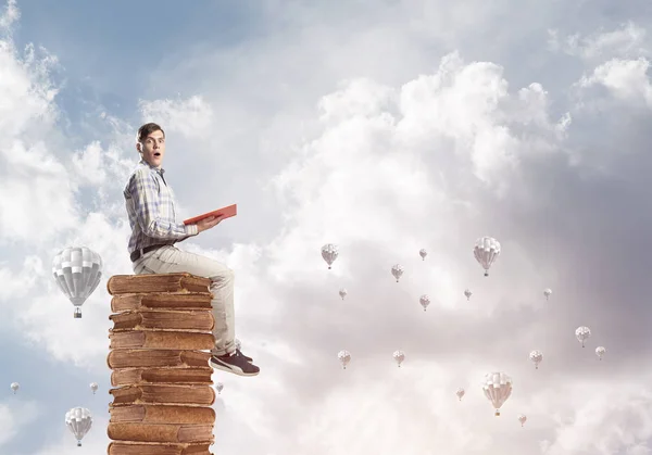 Joven Sorprendido Sentado Montón Libros Con Uno Las Manos — Foto de Stock