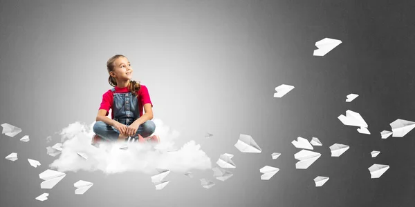 クラウドと紙飛行機の周りに座っているかわいい子供女の子 — ストック写真