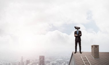 Evin çatısında baş durmak yerine kamerayla zum yapan yüzü olmayan bir iş adamı.