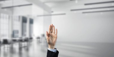 İş kadınının eli ekranda kapalı ve arka planda avuç içi ve ofis