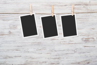 Boş fotoğraf çerçevesi ahşap bir zeminde ipte asılı.