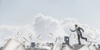 Takım elbise ile telefonu elinde kitap Clear sky ile arka plan üzerinde uçan arasında çalışan iş adamı. Karışık teknik.