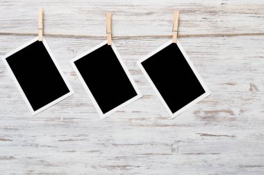 Boş fotoğraf çerçevesi ahşap bir zeminde ipte asılı.