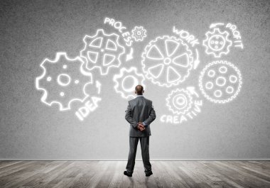 İş adamının çizilmiş dişli mekanizmasıyla duvara baktığı arka plan