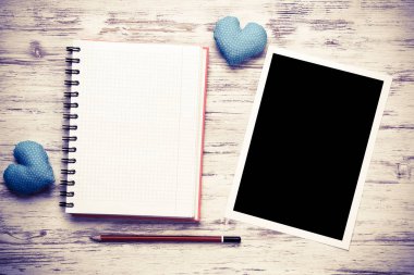 Boş fotoğraf çerçevesi ve tahta masanın üzerindeki not defteri.