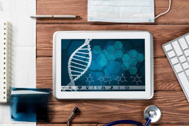Beyaz tablet bilgisayar ve doktor aletleri ahşap masada.
