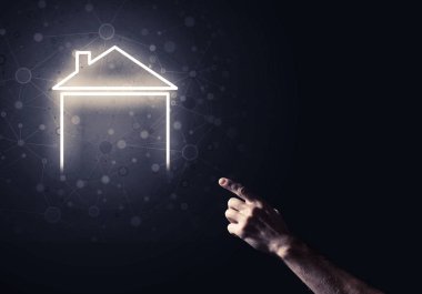 İnsanın eli parlayan ev simgesi ya da sembolüyle dokunuyor