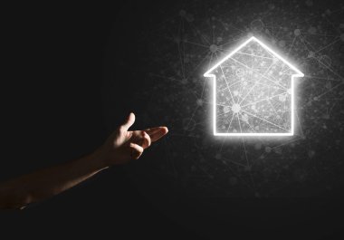 İnsanın eli parlayan ev simgesi ya da sembolüyle dokunuyor