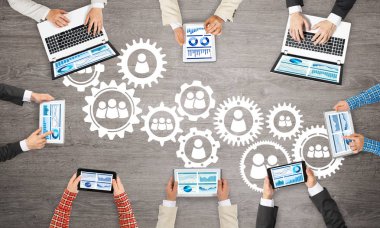 Ellerinde cihazlar bulunan bir grup insan, iletişim ve ağın sembolü olarak birlikte çalışıyor.