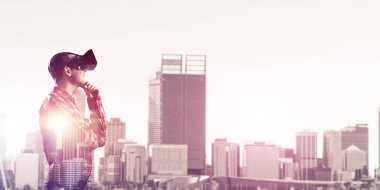 Sanal gerçeklik kulaklığı olan genç bir adam ya da şehrin arka planında 3 boyutlu gözlüklü.