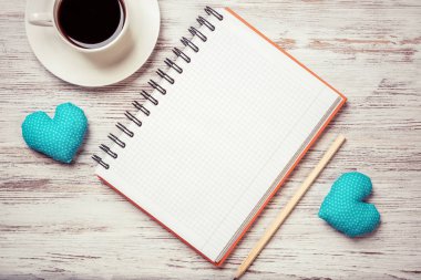 Kahve fincanı not defteri kalem ve ahşap yüzeyde iki kalp