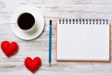 Kahve fincanı not defteri kalem ve ahşap yüzeyde iki kırmızı kalp