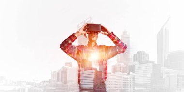 Sanal gerçeklik kulaklığı olan genç bir adam ya da şehrin arka planında 3 boyutlu gözlüklü.