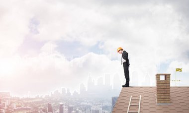 Takım elbiseli genç işadamı ve çatıda kask var. Karışık ortam