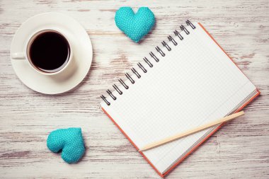 Kahve fincanı not defteri kalem ve ahşap yüzeyde iki kalp