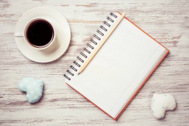 Kahve fincanı not defteri kalem ve ahşap yüzeyde iki kalp