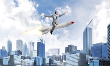 Arka plan üzerinde modern cityscape gökdelenler ve mavi gökyüzü ile roket üzerinde uçan takım elbiseli Genç ve mutlu işadamı kavramsal görüntü.