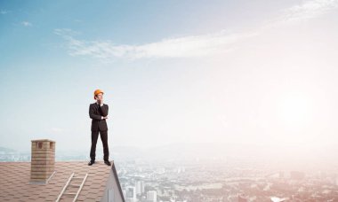 Takım elbiseli genç işadamı ve çatıda kask var. Karışık ortam