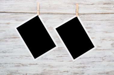 Boş fotoğraf çerçevesi ahşap bir zeminde ipte asılı.