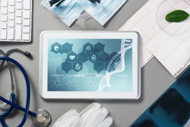 Gri yüzeyde beyaz tablet ve doktor araçları