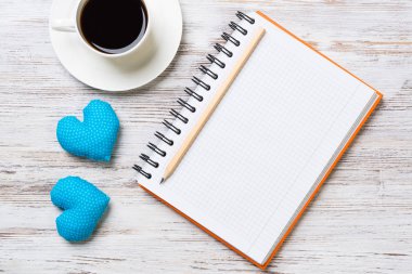 Kahve fincanı not defteri kalem ve ahşap yüzeyde iki kalp