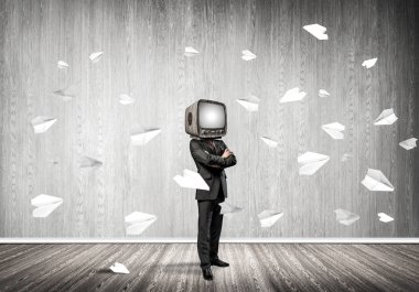 Kağıt uçaklar ile gri karanlık duvar boş oda içinde arka planda uçan arasında dururken kafasına silah tutmak yerine eski Tv ile takım elbiseli işadamı geçti.