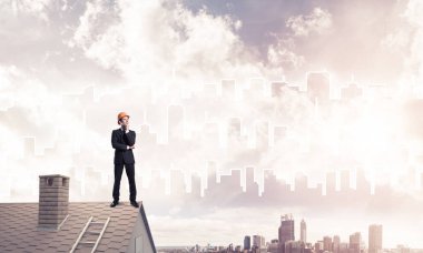 Takım elbiseli genç işadamı ve çatıda kask var. Karışık ortam