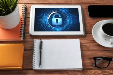 Ofis eşyalarıyla iş yeri ve ekranda asma kilit simgeleri olan tablet