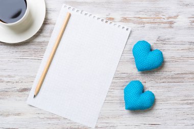 Kahve fincanı not defteri kalem ve ahşap yüzeyde iki kalp