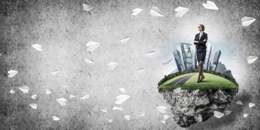 Yeşil yüzen adada beton zemine karşı duran kendine güvenen zarif bir iş kadını.