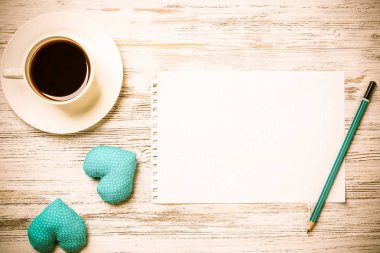 Kahve fincanı not defteri kalem ve ahşap yüzeyde iki kalp