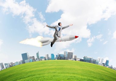 Cityscape ve mavi gökyüzü arka plan üzerinde ile roket üzerinde uçan takım elbiseli genç işadamı kavramsal görüntü.