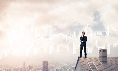 Takım elbiseli genç işadamı ve çatıda kask var. Karışık ortam