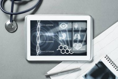 Gri yüzeyde beyaz tablet ve doktor araçları