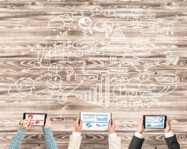 Ellerinde cihazlar bulunan üç kişilik bir grup iletişim ve ağ oluşturma sembolü olarak birlikte çalışıyor.