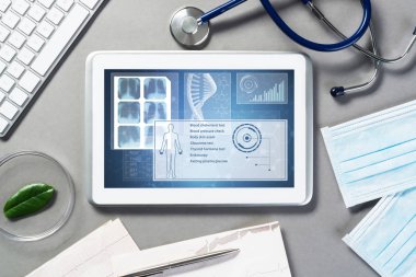 Gri yüzeyde beyaz tablet ve doktor araçları