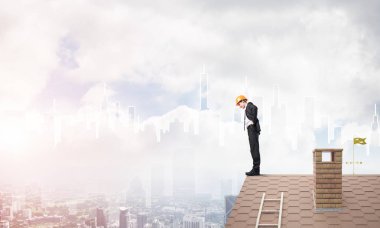 Takım elbiseli genç işadamı ve çatıda kask var. Karışık ortam