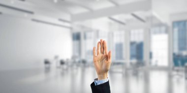 İş kadınının eli ekranda kapalı ve arka planda avuç içi ve ofis