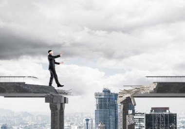Gizli tehditlerin ve risklerin sembolü olarak beton köprüde gözü kapalı yürüyen bir iş adamı. Arka planda şehir manzarası. 3B görüntüleme.