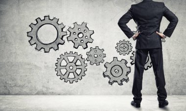 İş adamının çizilmiş dişli mekanizmasıyla duvara baktığı arka plan