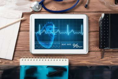 Beyaz tablet bilgisayar ve doktor aletleri ahşap masada.