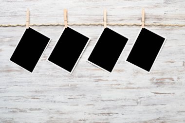 Boş fotoğraf çerçevesi ahşap bir zeminde ipte asılı.