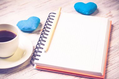 Kahve fincanı not defteri kalem ve ahşap yüzeyde iki kalp