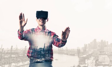 Sanal gerçeklik kulaklığı olan genç bir adam ya da şehrin arka planında 3 boyutlu gözlüklü.