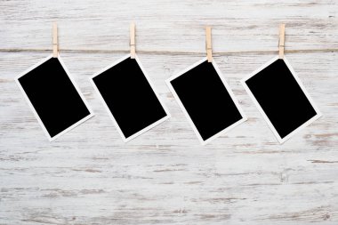 Boş fotoğraf çerçevesi ahşap bir zeminde ipte asılı.