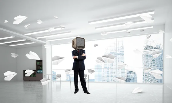 Businessman in suit with an old TV instead of head keeping arms crossed while standing among flying paper planes inside office building. 3D rendering.