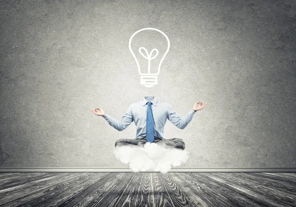 Businessman sitting in lotus pose and light bulb instead of his head