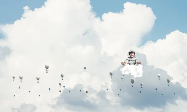 空を背景に曇った空を飛ぶ気球の間で瞑想しながら 目を閉じて集中して見ている若い男の子 — ストック写真