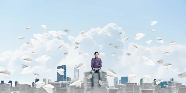 Ein Junger Mann Lässiger Kleidung Sitzt Inmitten Fliegender Papierflugzeuge Mit — Stockfoto